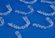 Bildnachweis für: Invisible orthodontics cosmetic brackets on blue background, too